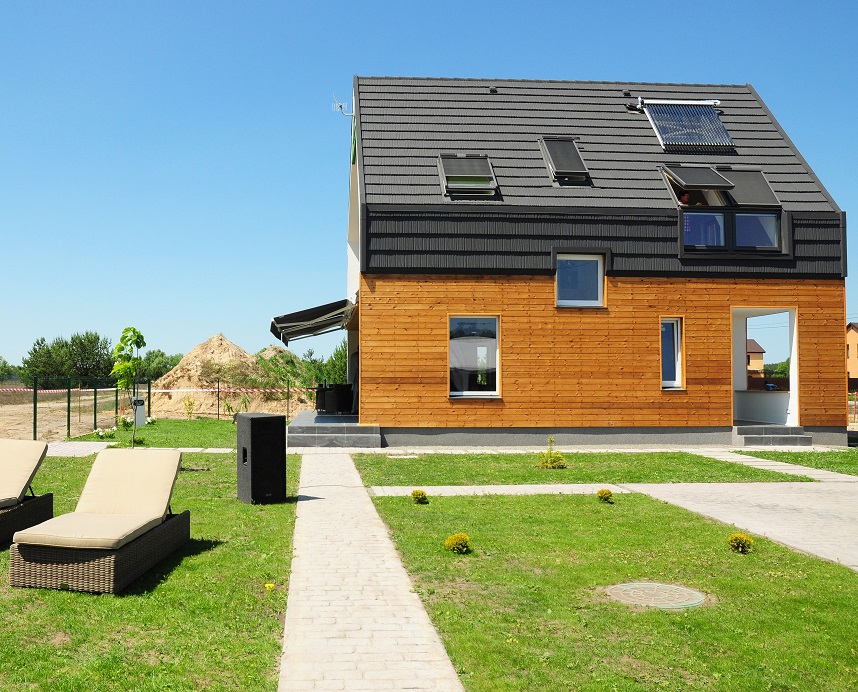 nowoczesny, drewniany dom, z grafitowym dachem, licznymi oknami i panelami fotowoltaicznymi, wykonany w technologii budownictwa pasywnego